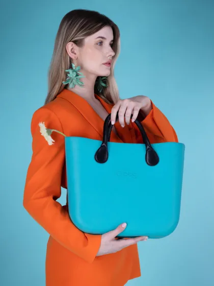 Live model fashion still, teal bag and orange suit